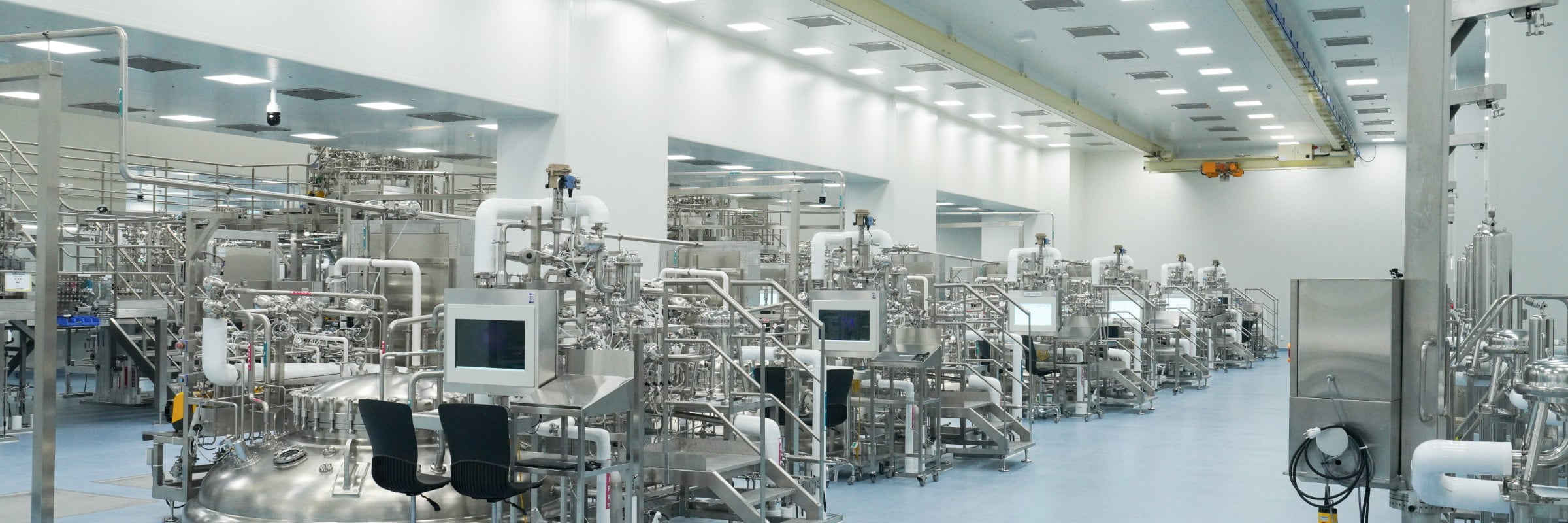 Wide view of a large-scale bioprocessing facility filled with stainless steel pipes and reactors.