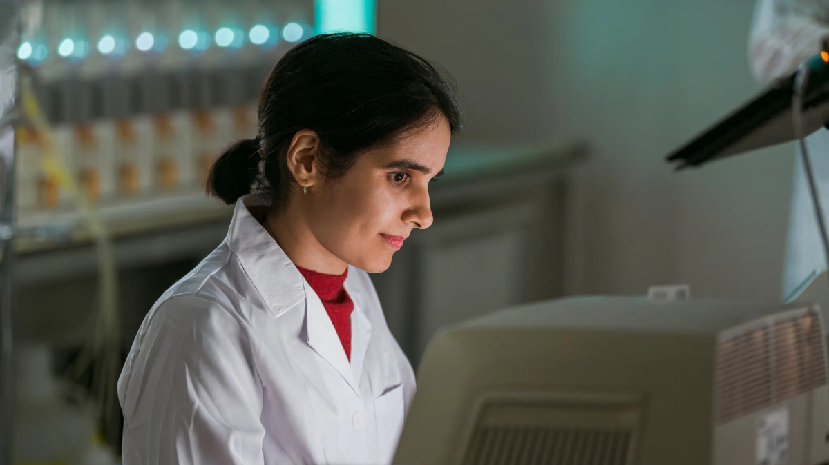 An employee performing a manual visual inspection for foreign substances in vials.